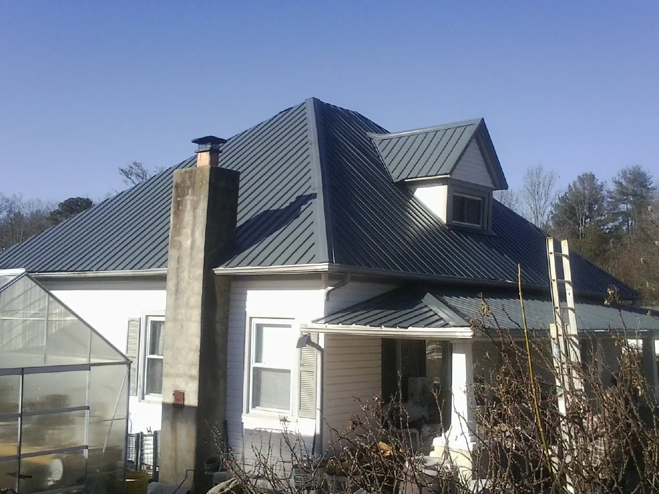 Dark blue standing seam metal roof on a white farmhouse with dormer — Slate & Tile Roof Repair by Roofing Brothers in Columbia