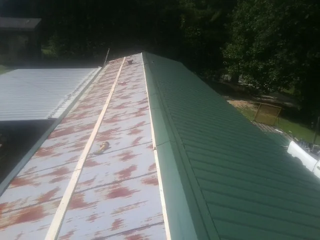 Old rusted panels beside newly installed green metal roofing — Wind Damage Roof Repair by Roofing Brothers in Columbia